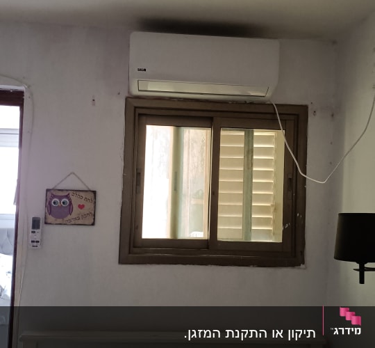 מזגן מותקן מעל חלון בחדר שינה